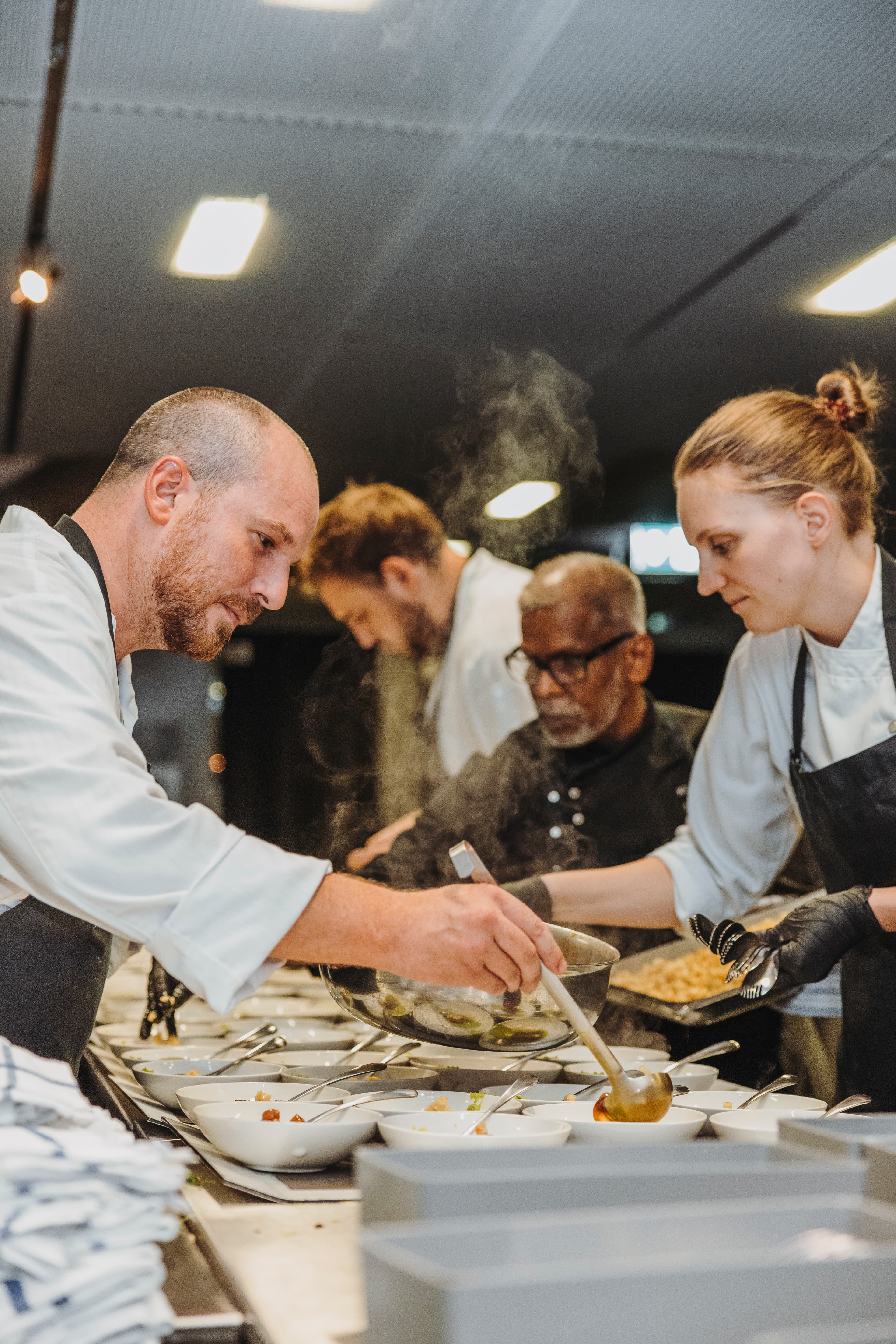 Mitarbeitende der Küche schöpfen die Gerichte des KKL Luzern Event Caterings